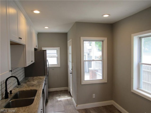 kitchen featuring white cabinets, light stone countertops, and sink