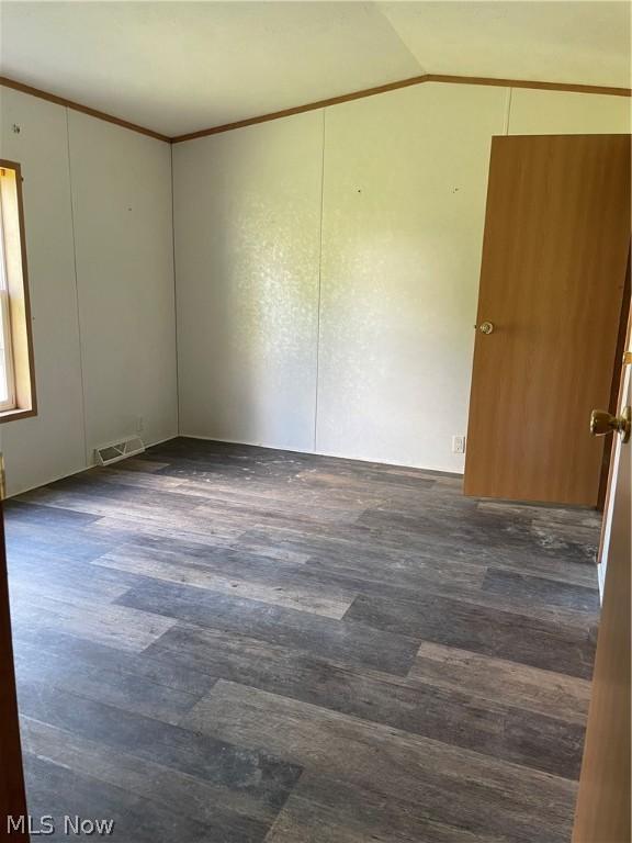 empty room with dark wood-type flooring and lofted ceiling