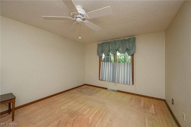 carpeted empty room with ceiling fan and a textured ceiling