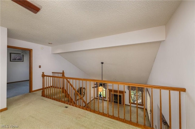 interior space with a textured ceiling, carpet floors, and vaulted ceiling