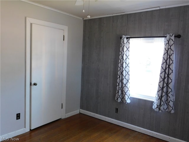 spare room featuring crown molding, wood walls, and dark hardwood / wood-style floors