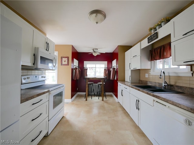 kitchen featuring white cabinets, a healthy amount of sunlight, backsplash, sink, and white appliances