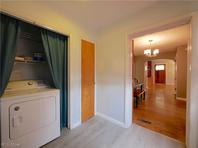 washroom featuring light hardwood / wood-style flooring, an inviting chandelier, and washer / clothes dryer