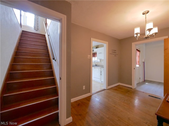 stairway with sink, a chandelier, and hardwood / wood-style flooring