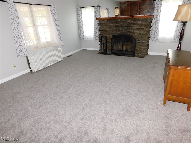 unfurnished living room featuring a healthy amount of sunlight, carpet flooring, and a fireplace