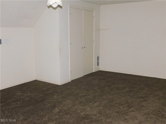 additional living space featuring lofted ceiling and dark colored carpet