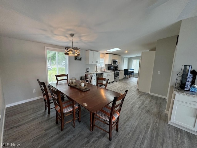 dining space with a skylight, dark wood-type flooring, and sink