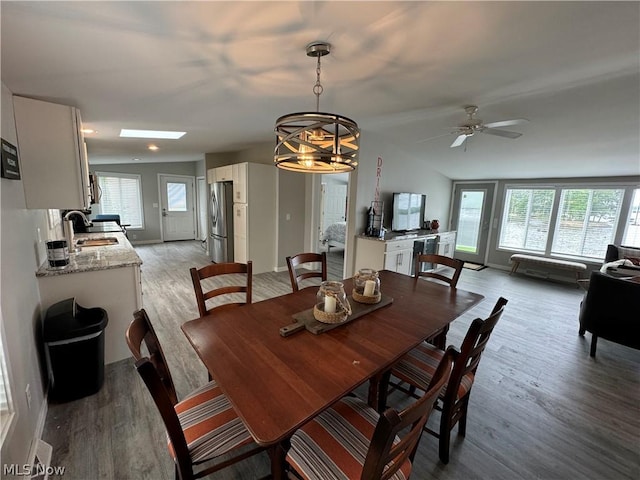 dining space with ceiling fan with notable chandelier, light hardwood / wood-style floors, sink, and a wealth of natural light