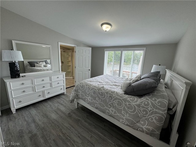 bedroom featuring vaulted ceiling, ensuite bath, and dark wood-type flooring