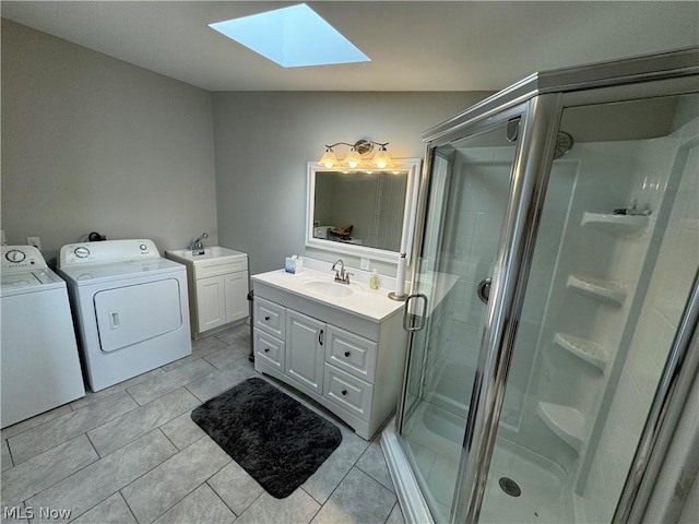 bathroom with tile patterned floors, lofted ceiling with skylight, a shower with door, washer and clothes dryer, and vanity