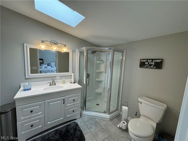 bathroom featuring vanity, a skylight, tile patterned flooring, toilet, and an enclosed shower