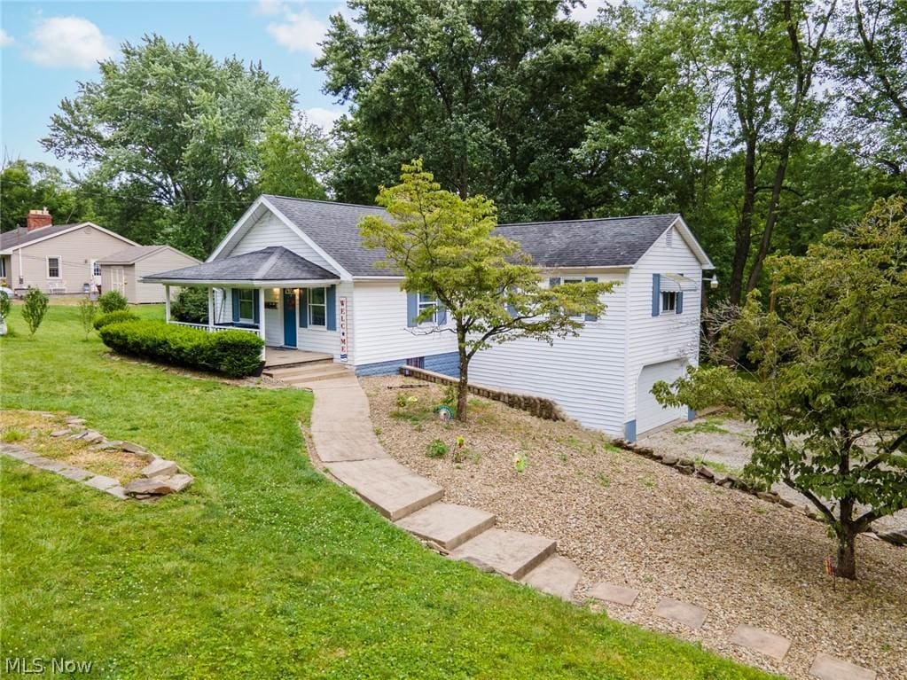 ranch-style home featuring a porch, a garage, and a front lawn