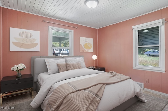 carpeted bedroom with wooden walls, wooden ceiling, and ornamental molding