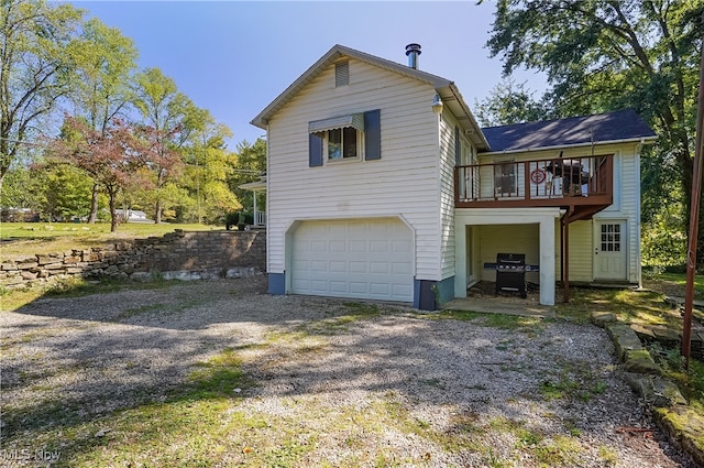 back of house with a garage and a deck