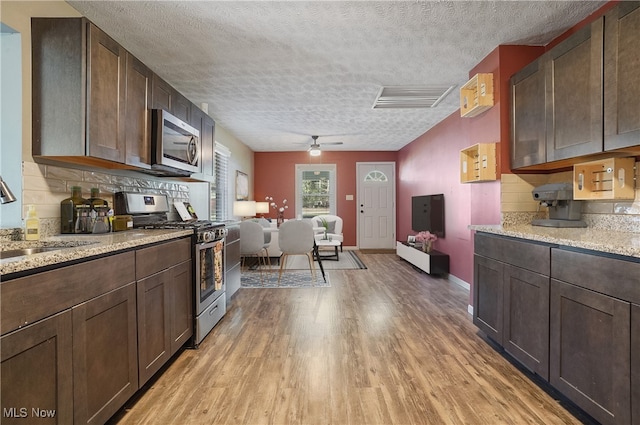 kitchen featuring appliances with stainless steel finishes, backsplash, dark brown cabinetry, ceiling fan, and light hardwood / wood-style flooring