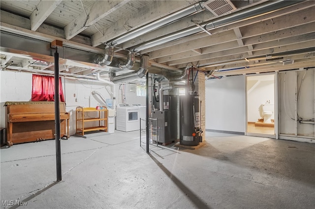 basement with washing machine and dryer, gas water heater, and heating unit