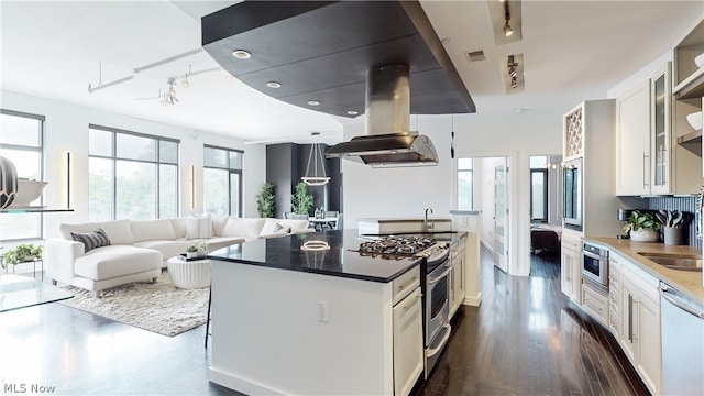 kitchen with white cabinetry, a center island, dark wood-type flooring, stainless steel appliances, and island range hood