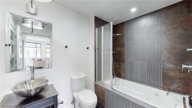 full bathroom featuring vanity, tiled shower / bath combo, and toilet