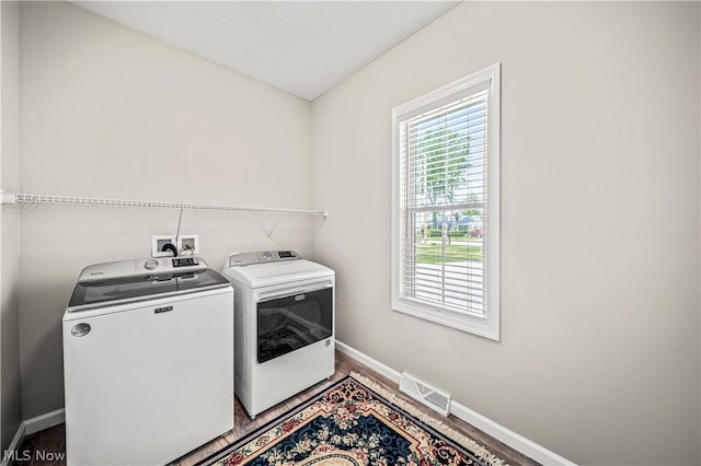 washroom with light wood-style flooring, laundry area, visible vents, baseboards, and washer and dryer