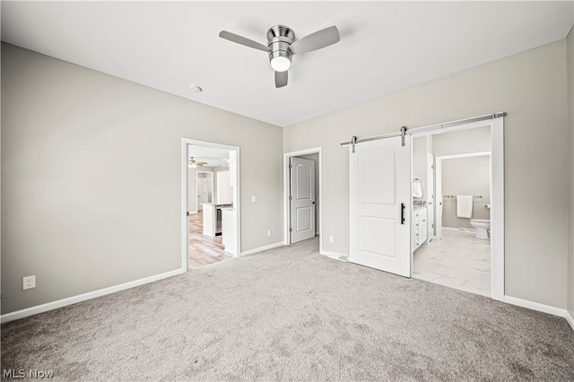 unfurnished bedroom featuring ensuite bathroom, carpet, ceiling fan, and a barn door