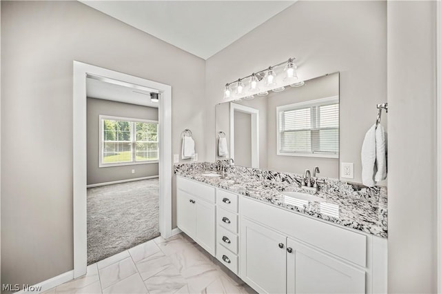 bathroom featuring marble finish floor, a sink, baseboards, and double vanity