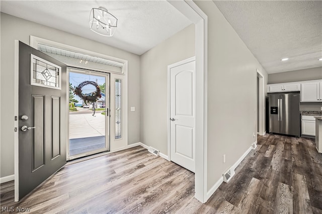 entrance foyer with an inviting chandelier, dark hardwood / wood-style floors, and a textured ceiling