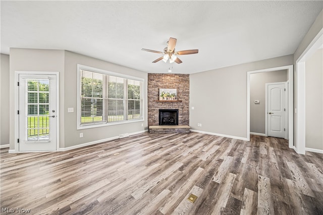 unfurnished living room with a stone fireplace, ceiling fan, and wood-type flooring