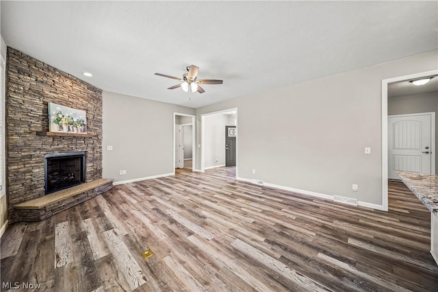 unfurnished living room with a ceiling fan, a fireplace, baseboards, and wood finished floors