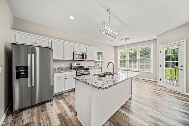 kitchen with sink, appliances with stainless steel finishes, white cabinets, and an island with sink