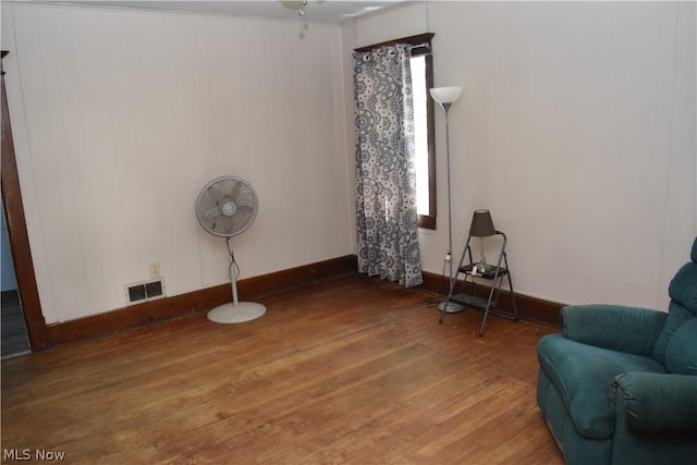 living area featuring wood finished floors, visible vents, and baseboards