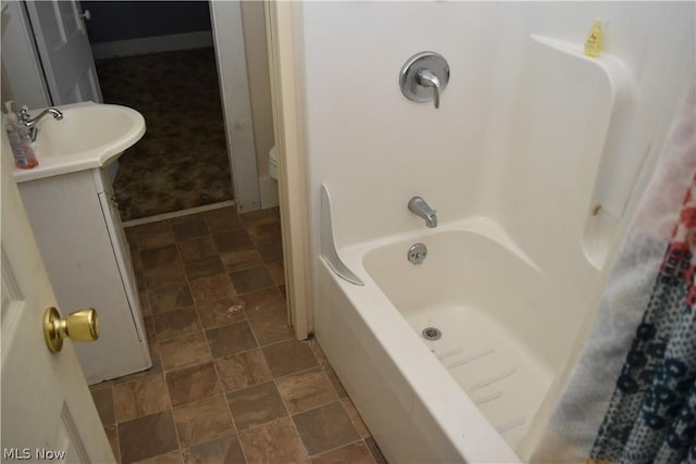 full bath with stone finish floor, vanity, and baseboards