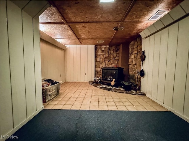 304 Stone Rd, Belpre, OH 45714 - unfurnished living room with a wood stove, wood walls, and light tile patterned floors