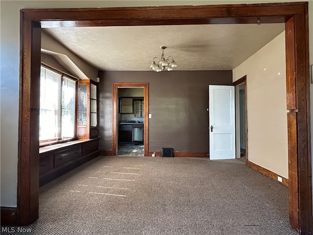 unfurnished living room featuring dark carpet, a textured ceiling, and a chandelier