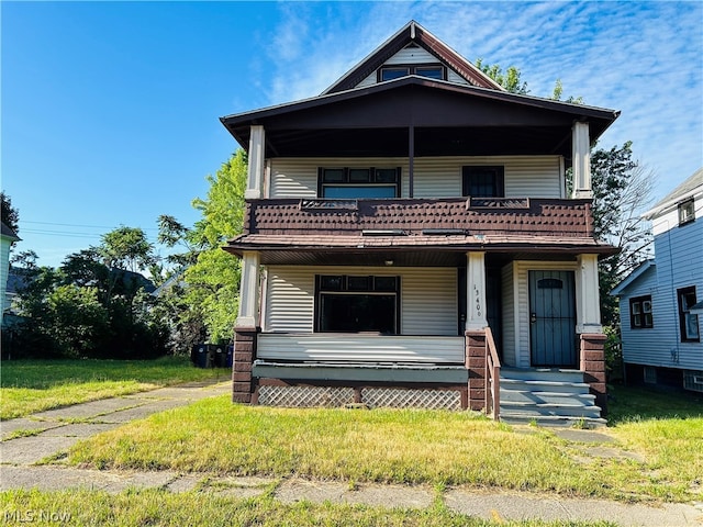 view of property featuring a balcony and a front yard