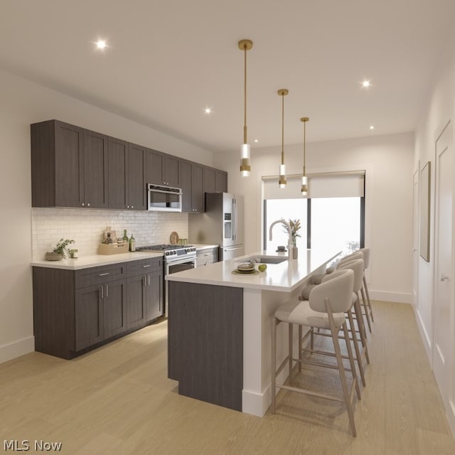 kitchen with decorative backsplash, stainless steel appliances, light hardwood / wood-style floors, and an island with sink