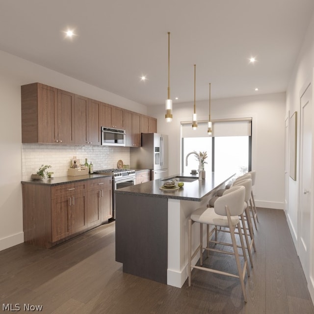 kitchen featuring appliances with stainless steel finishes, dark hardwood / wood-style floors, tasteful backsplash, and a center island with sink