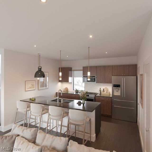 kitchen with appliances with stainless steel finishes, a breakfast bar area, sink, decorative backsplash, and dark hardwood / wood-style floors