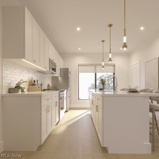 kitchen featuring white cabinetry, light wood-type flooring, stainless steel range oven, pendant lighting, and a center island with sink