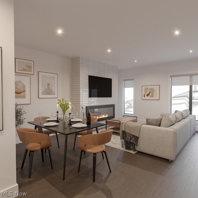 living room with wood-type flooring, brick wall, and a large fireplace