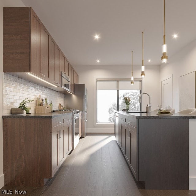 kitchen featuring wood-type flooring, hanging light fixtures, decorative backsplash, sink, and appliances with stainless steel finishes