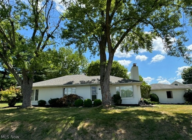 ranch-style house with stucco siding, a chimney, and a front yard