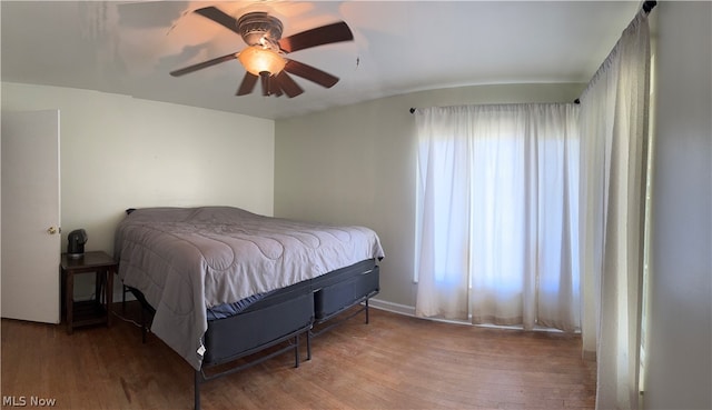 bedroom with multiple windows, wood-type flooring, and ceiling fan