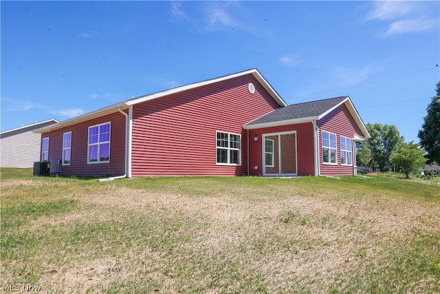 rear view of property featuring central AC unit and a lawn