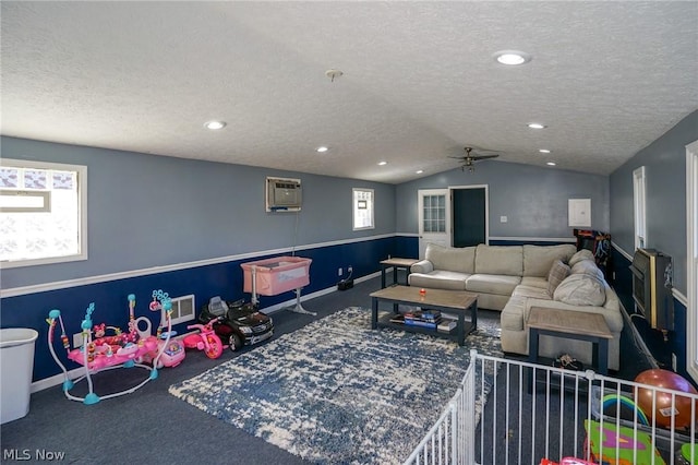 carpeted living room featuring a textured ceiling, a wall mounted AC, and vaulted ceiling