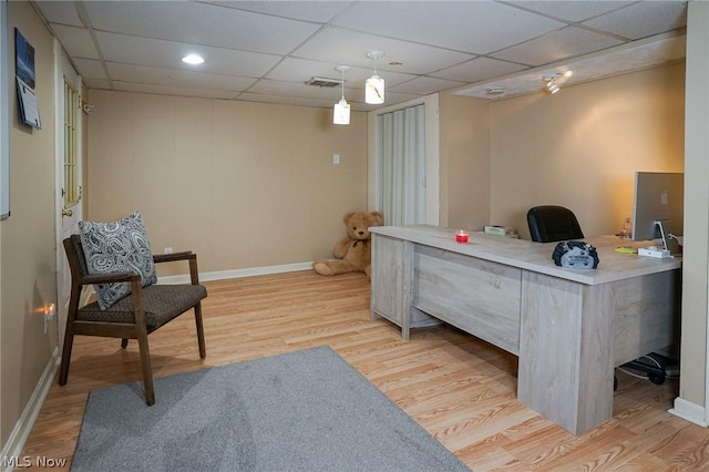 office with light hardwood / wood-style flooring and a paneled ceiling