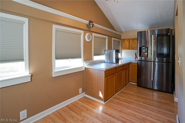 kitchen featuring a healthy amount of sunlight, vaulted ceiling, stainless steel fridge, and light hardwood / wood-style flooring