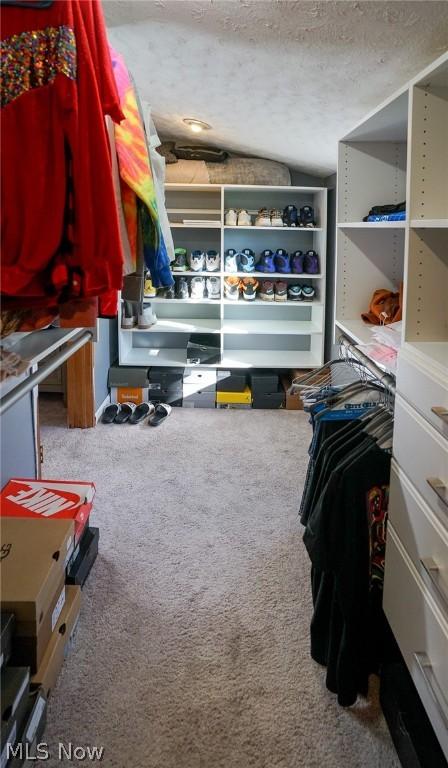 walk in closet with carpet and vaulted ceiling