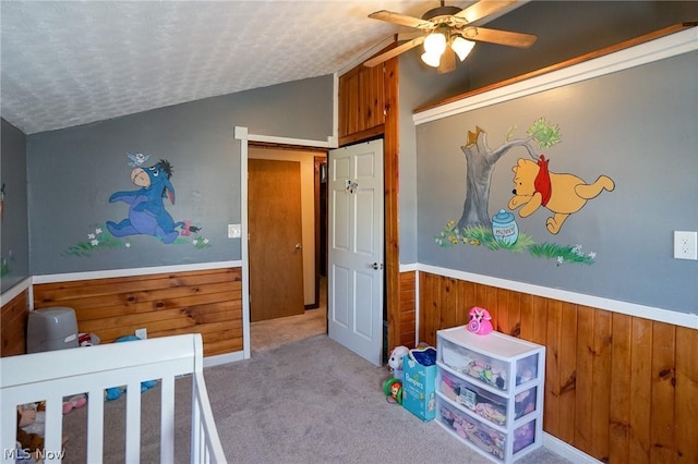 bedroom with ceiling fan, light colored carpet, vaulted ceiling, and a textured ceiling