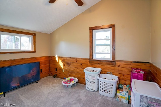 rec room featuring lofted ceiling, light colored carpet, ceiling fan, and wooden walls