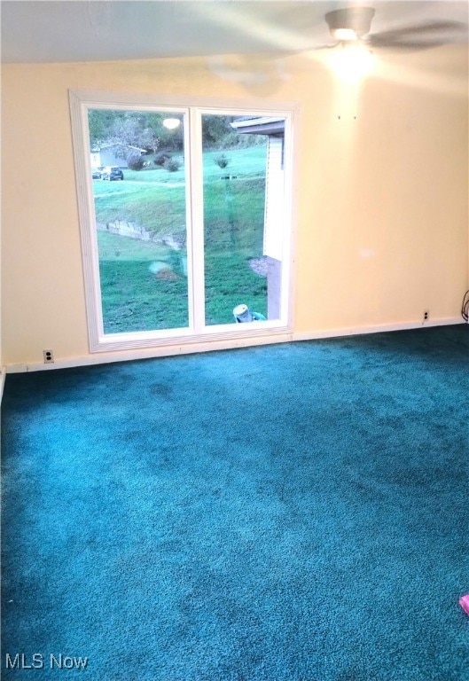 empty room featuring dark colored carpet and ceiling fan